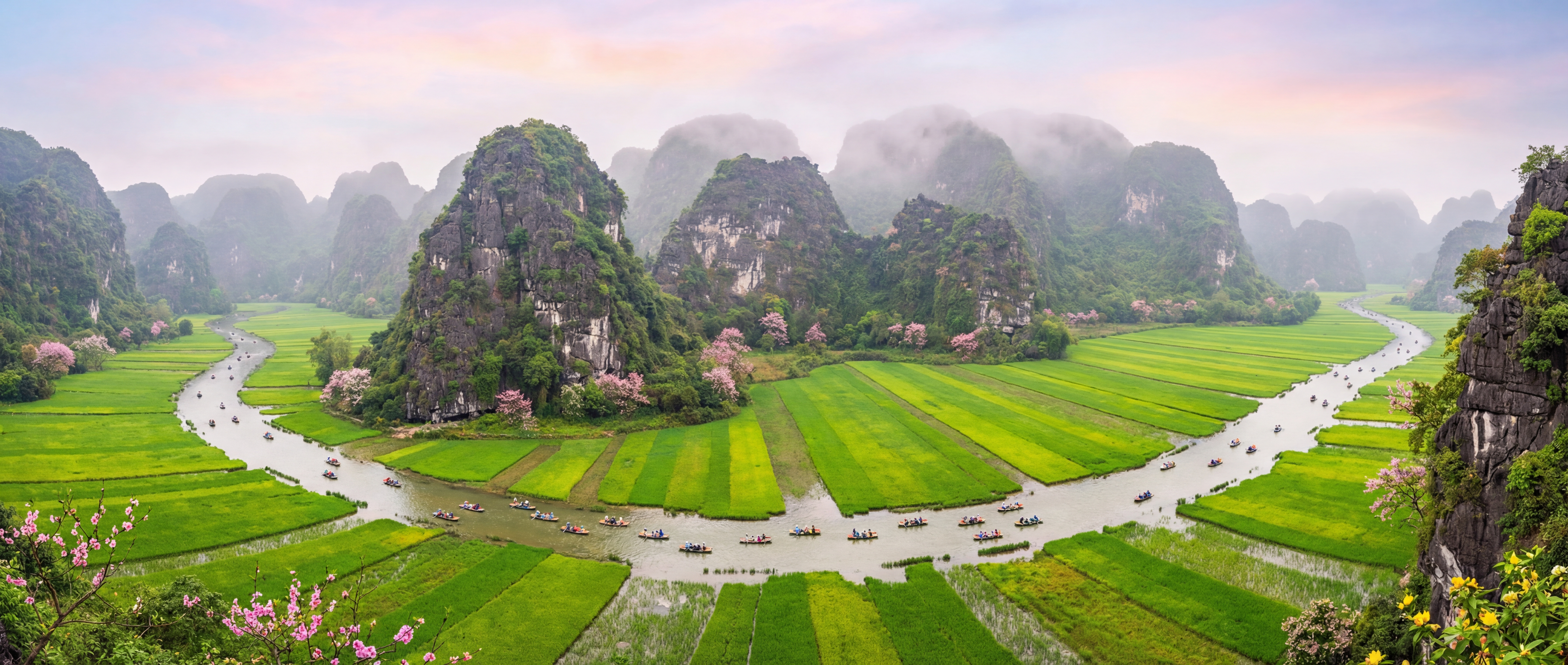 Panoramic view of Ninh Binh landscape in spring with limestone karst mountains, river, and green veg